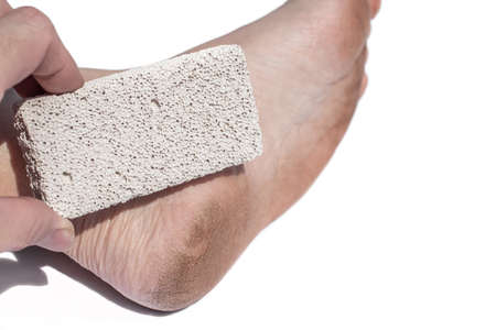 Man cracked heel and a pumice stone, volcanic rock. Dirt cracked feet due to walking barefoot.の写真素材