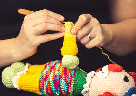 Hand of a woman using a knitting needle to sew a crochet clown doll. Handmade kids toy.の写真素材