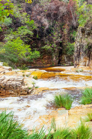 Waterfalls with golden tones, sedimentary rocks and the green vegetation of the Cerrado Mineiro at...