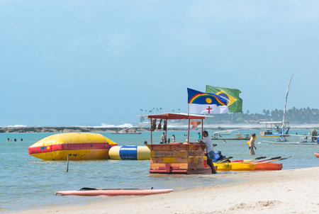 Ipojuca, PE, Brazil - October 15, 2021: floating bar and aquatic sports at Muro Alto beach, the famous paradise beach of Porto de Galinhas with warm and calm water surrounded by a reef wall.のeditorial素材