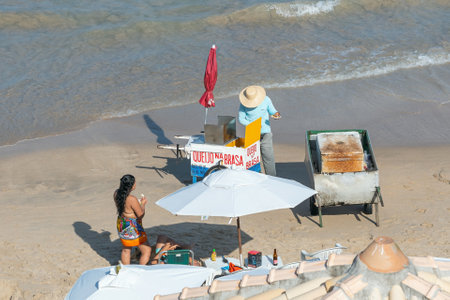 Ipojuca, PE, Brazil - October 15, 2021: man selling grilled cheese and drinks on a food cart at Porto de Galinhas beach.のeditorial素材