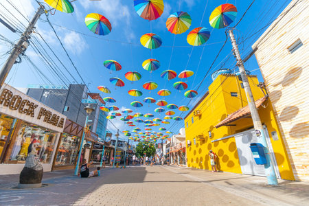 Ipojuca, PE, Brazil - October 15, 2021: street decorated with colored frevo umbrellas in Porto de Galinhas downtown on a beautiful sunny day. Rua das Piscinas Naturais street, tourist destination.のeditorial素材