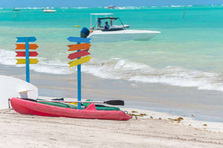 Kayaks on the sand of a beautiful beach and multiple colored signposts. No writing on signposts. Photo taken in Maragogi - AL, Brazil.の写真素材