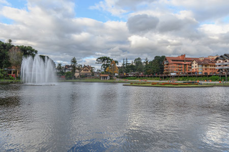 Gramado, RS, Brazil - May 16, 2022: Joaquina Rita Bier lake, an artificial lake with a small island and a fountain, with trees, houses and hotels around. Tourist destination of Gramado.のeditorial素材