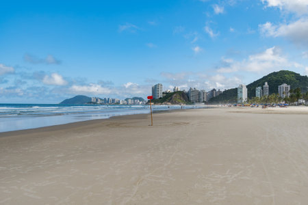 View of Enseada Beach, a beautiful beach with a view of the sand, the sea on a blue sky day and few clouds. Guaruja - SP, Brazil.の写真素材