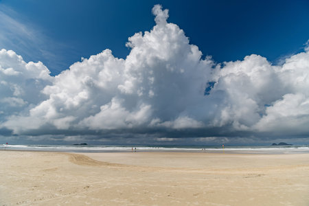 Morning at Enseada Beach on a beautiful sunny day with some rain clouds around, view of the beach sand and the sea. Guaruja - SP, Brazil.の写真素材