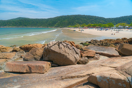 Guaiuba Beach, Guaruja SP, Brazil. Sunny day over the small bay with tranquil sea. Image of leisure and tourism on the Sao Paulo coast. Hills covered in Mata Atlantica vegetation frame the view.の写真素材