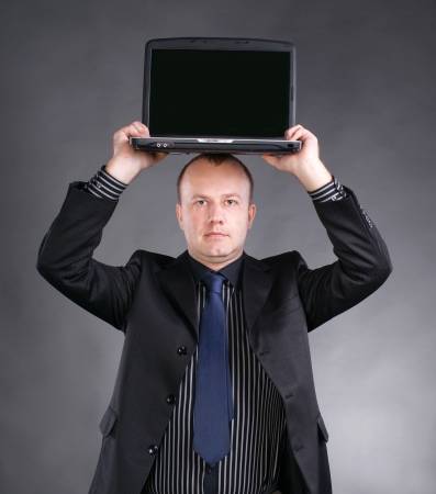 Young  businessman holding laptop on his head on a gray backgroundの写真素材