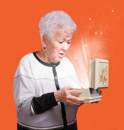 Senior woman with present box on an orange backgroundの写真素材