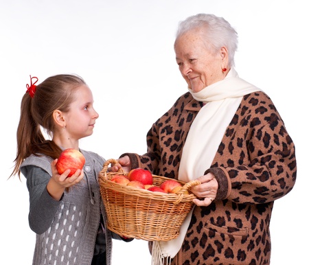 Grandmother with granddaughter with basket of apples on a white backgroundの写真素材
