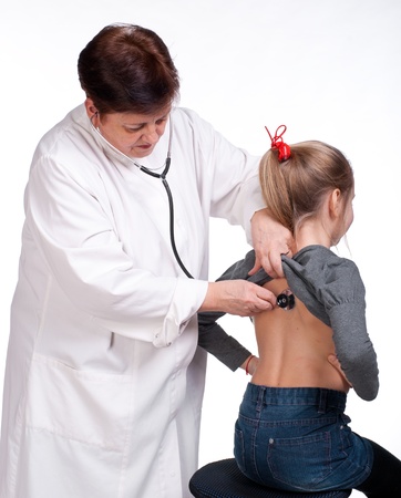 Senior doctor listening girl with stethoscope on a white backgroundの写真素材