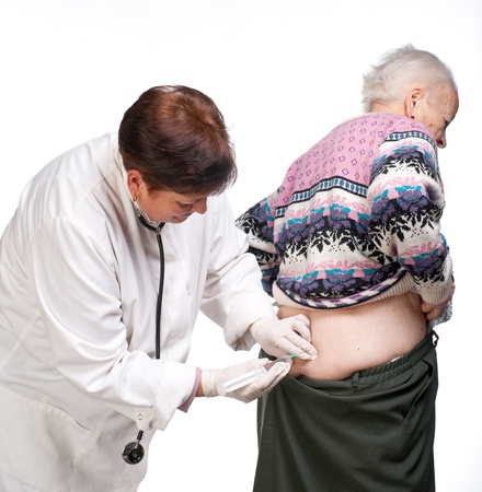 Doctor giving injection to old woman on a white backgroundの写真素材