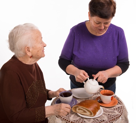 Mother having tea with her daughter on a white backgroundの写真素材