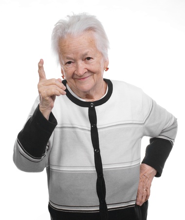 Portrait of a happy old woman pointing upwards isolated on whiteの写真素材