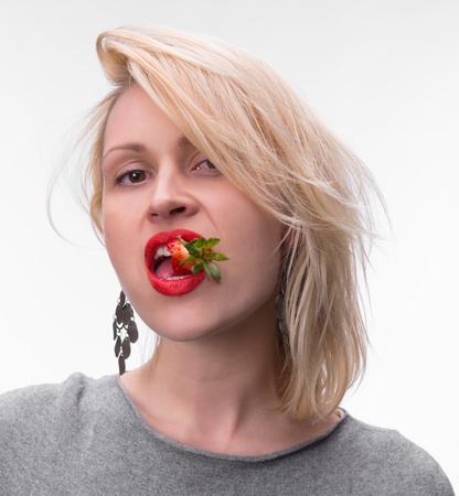Portrait of a woman enjoying eating strawberries on a white backgroundの写真素材