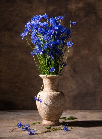 Beautiful blue cornflowers in vase on a wooden backgroundの写真素材