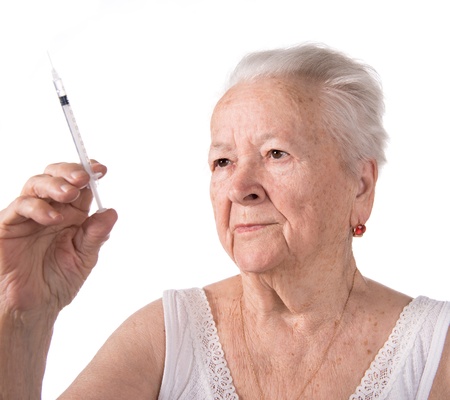 Old  woman preparing syringe for making insulin injection on a white backgroundの写真素材