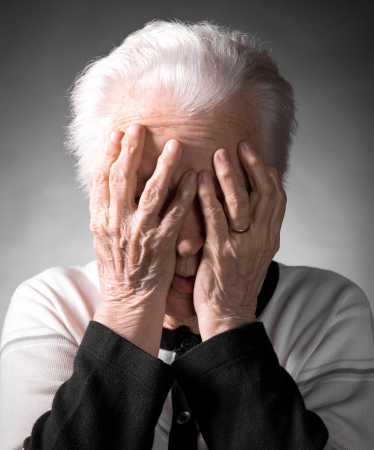 Old woman suffering from headache on a gray backgroundの写真素材