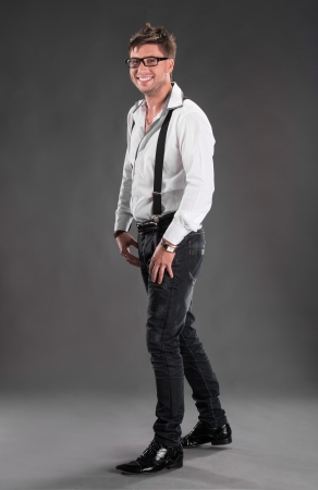 Full length photo of happy handsome young man in glassed on a gray backgroundの写真素材