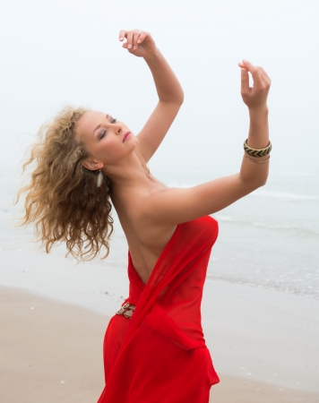 Beautiful nude woman posing in red fabric in morning fogの写真素材