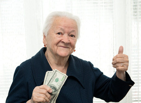 Portrait of an  woman holding money in hand and showing yes sign on white backgroundの写真素材