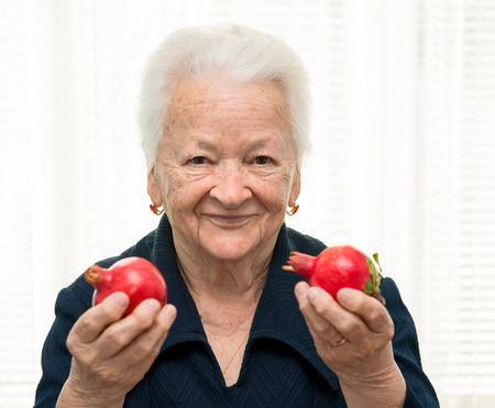 Portrait of old woman with pomegranates in her handsの写真素材