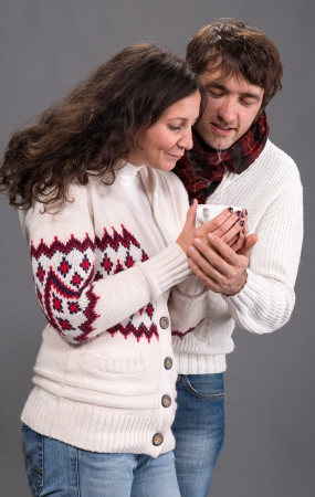 Adorable couple holding cup of coffee on a gray backgroundの写真素材
