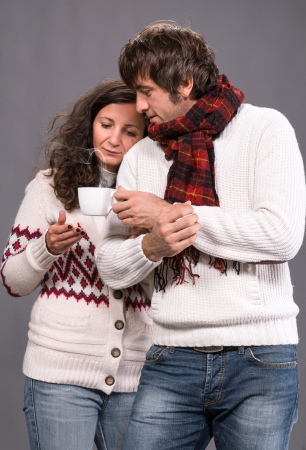Adorable couple holding cup of coffee on a gray backgroundの写真素材
