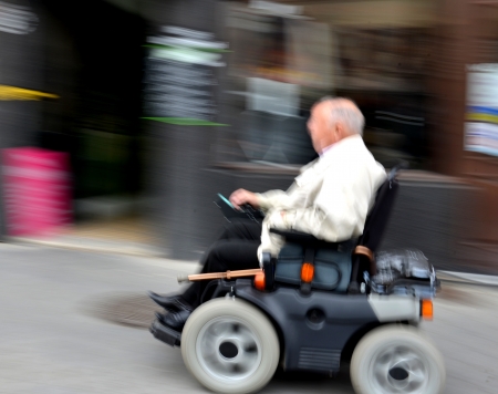 Invalid man on the wheelchair on a city street in motion blurの写真素材