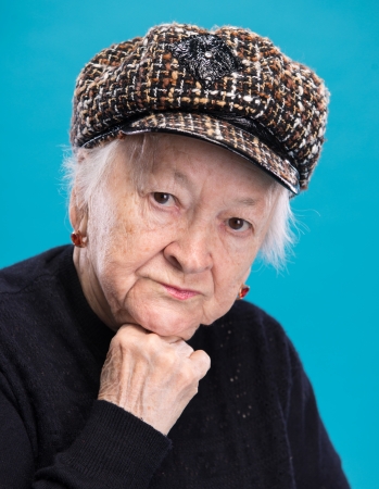 Portrait of old woman in hat on a blue backgroundの写真素材