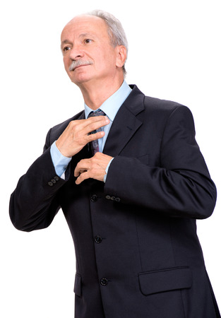 Businessman adjusting his tie on a white backgroundの写真素材