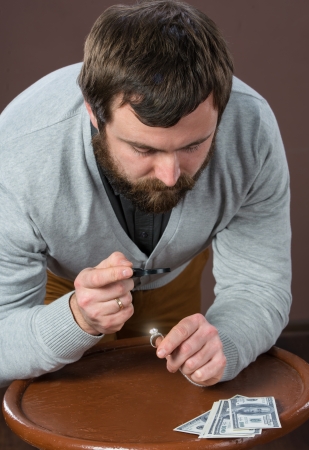 Man looking at jewelry through magnifying glassの写真素材