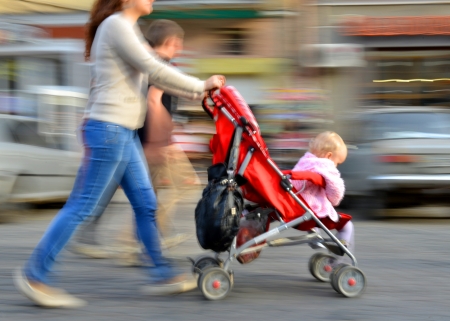 Mother walks with the child in the stroller  Intentional motion blur