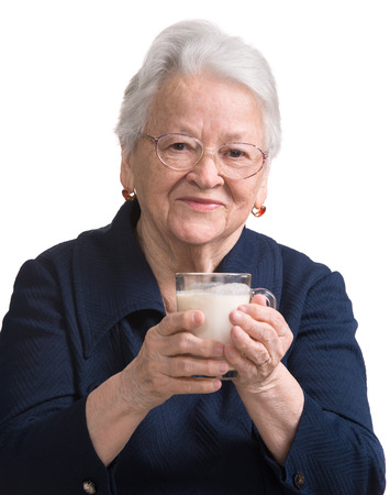 Healthy old woman holding a glass milk on a white backgroundの写真素材