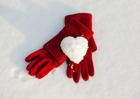 Red gloves and snow heart on snowの写真素材