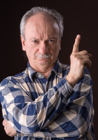 Angry elderly man pointing up on dark background  の写真素材