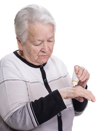 Old woman applying hand cream on a white backgroundの写真素材