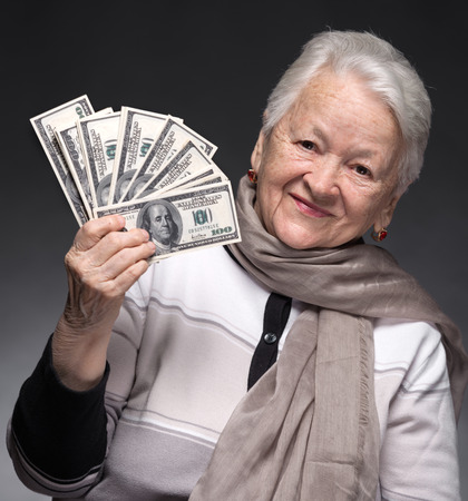 Smiling old woman holding money in handsの写真素材
