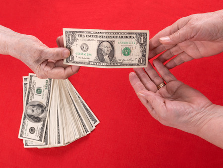 Hand handing over money to another hand on a red background