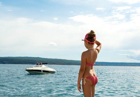 Beautiful girl in swimsuit  on the beach looking into the distanceの写真素材