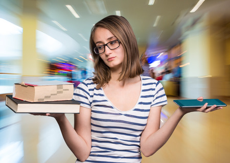 Pretty young girl holding a book in one hand and a tablet-pc in the otherの写真素材