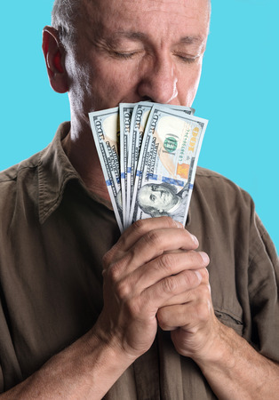 Lucky elderly man holding dollar bills on a blue backgroundの写真素材