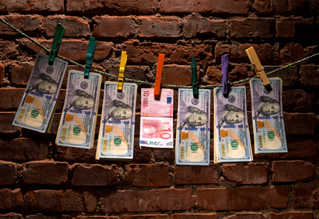 Dollar and euro bills  hanging on a rope attached with clothes pins.の写真素材
