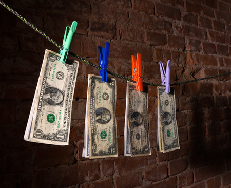 Dollar bills hanging on a rope attached with clothes pins.の写真素材