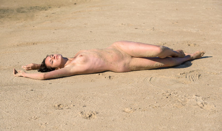 Beautiful young naked woman sunbathing on the beachの写真素材