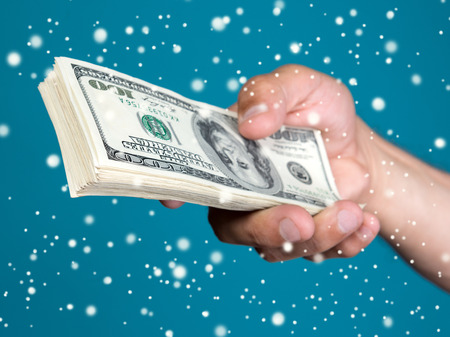 Man holding stack  of dollar bills on a blue background.  Christmas and holidays conceptの写真素材