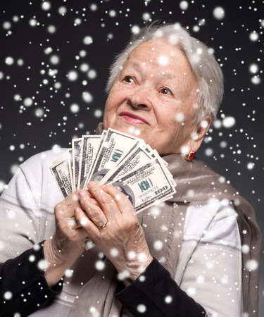 Smiling old woman holding money in hands. Christmas and holidays conceptの写真素材