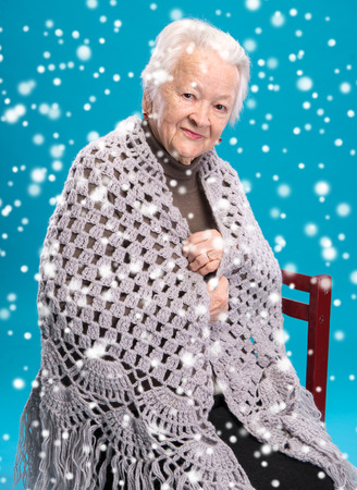 Old woman sitting in shawl on a chairの写真素材