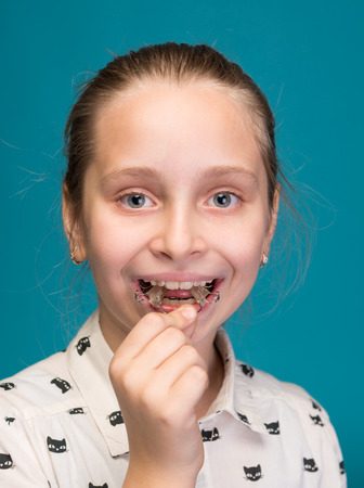 Happy girl holding dental braces on a blue backgroundの写真素材