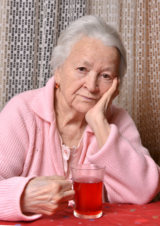 Portrait of old woman with cup of tea at homeの写真素材